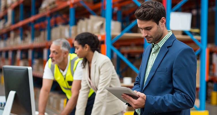 A businessman on his iPad with a factory in the background.