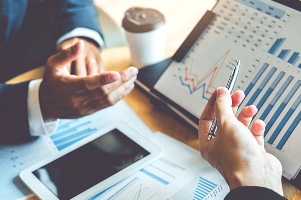 Two professionals discussing financial charts and graphs on a tablet and laptop, highlighting outsourced accounting services