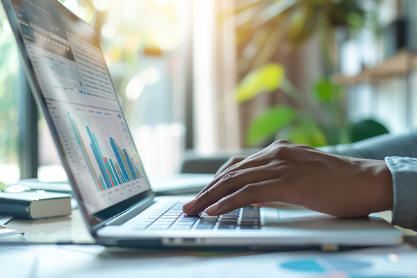 An individual using a laptop with financial analytics software open, symbolizing QuickBooks consulting services