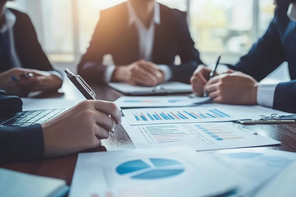 An experienced business consultant using a calculator and laptop to perform a detailed business valuation services for a client.