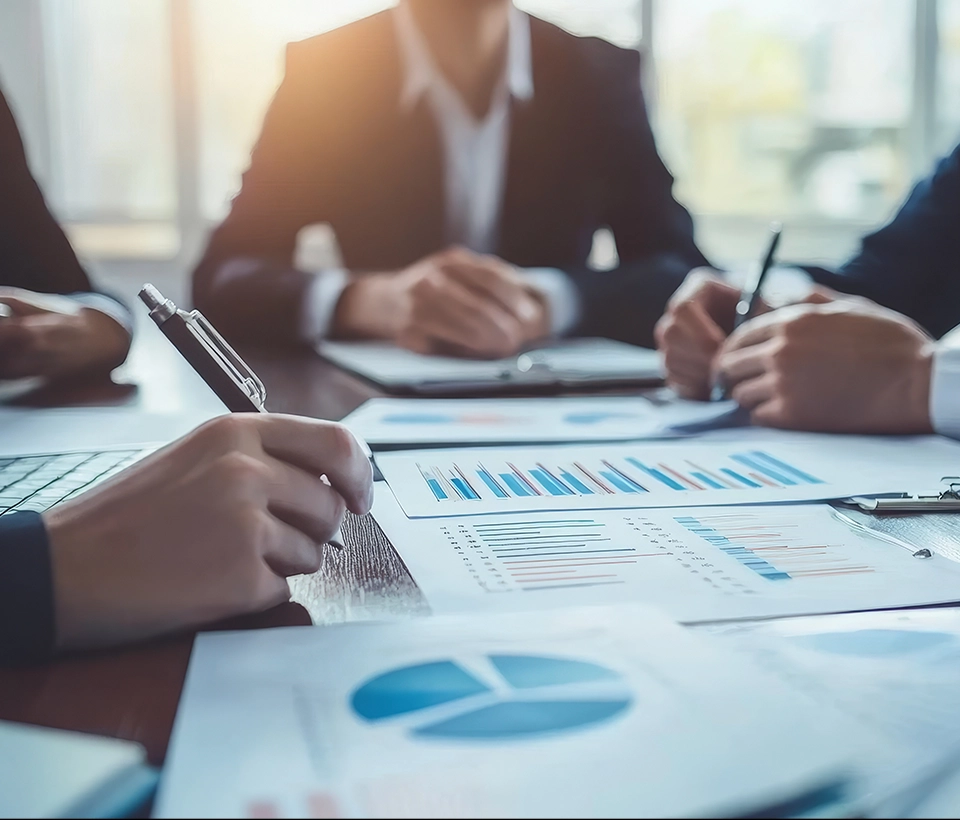 An experienced business consultant using a calculator and laptop to perform a detailed business valuation service for a client.